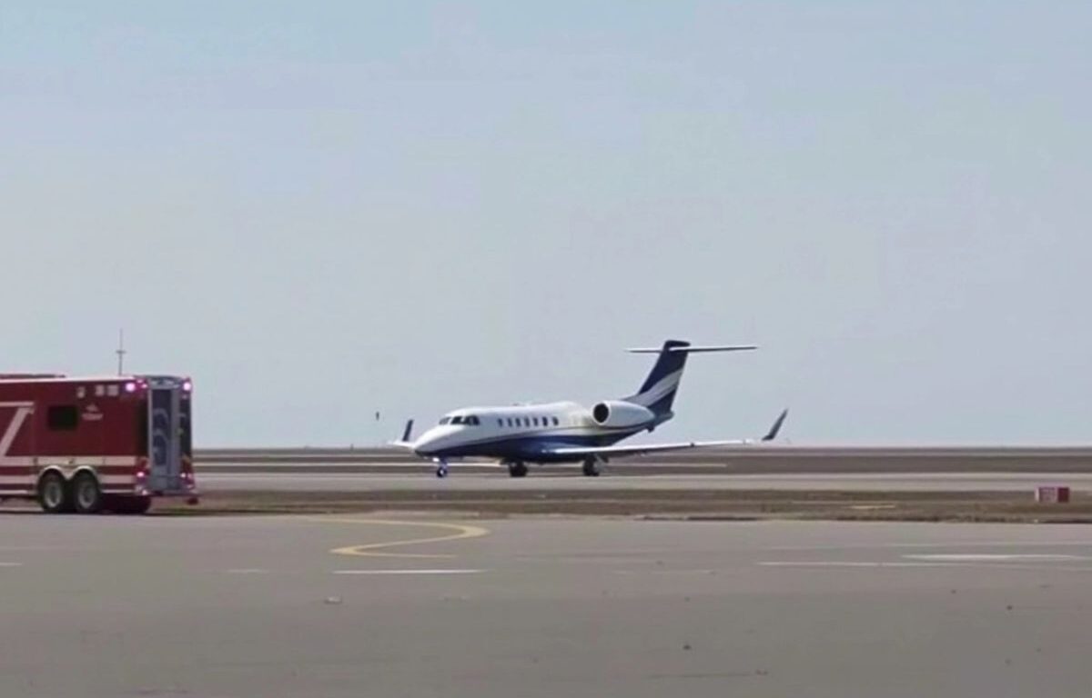 Private jet on runway with emergency vehicles nearby.