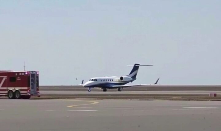 Private jet on runway with emergency vehicles nearby.